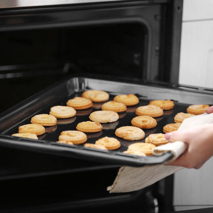 A person uses an oven mitt to place a baking tray full of small, round pastries or cookies into an open Empava 24 in 2.3 Cu. ft. Gas Wall Oven - Only For LPG. The baked goods are golden brown and arranged neatly on the tray.
7
