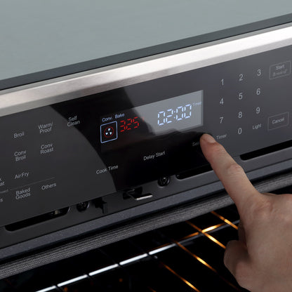 A close-up of a finger pressing buttons on the control panel of the Empava 30" Electric Single Wall Oven with its 4-layer glass door. The display shows the oven is set to "Conv. Bake" mode at 325°F with a timer of 2 hours and 20 minutes. The oven door is slightly open, revealing the inside.8