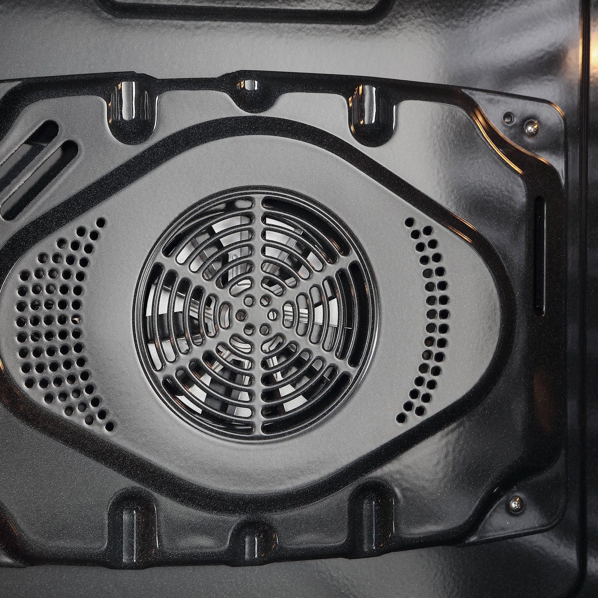 close-up-view-of-the-interior-of-an-empava-30-electric-single-wall-oven-the-image-focuses-on-the-back-panel-which-features-a-circular-vent-with-multiple-concentric-rings-and-perforations-the-metallic-surface-of-the-oven-appears-clean-and-polished-showcasing-its-steam-self-clean-function-for-effortless-maintenance